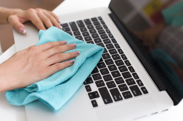 Mulher limpando teclado do notebook com pano de microfibra