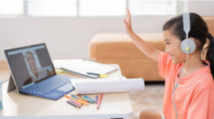 menina asiatica assistindo a uma aula online em casa