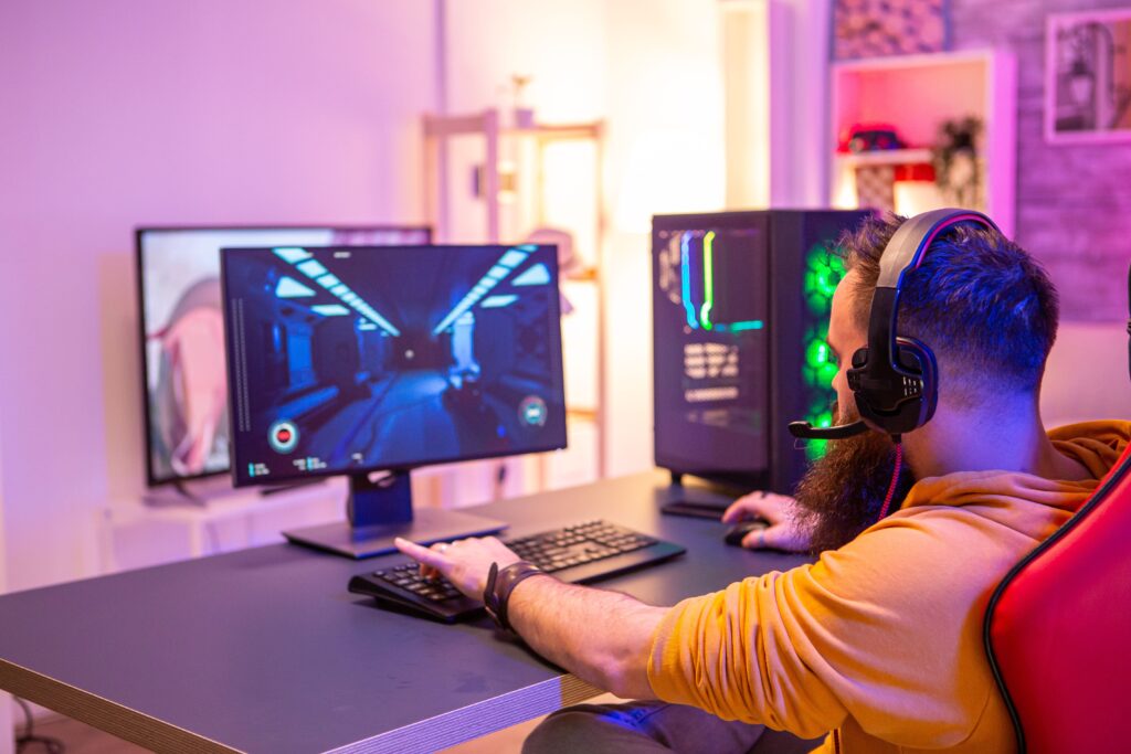 Homem sentado em frente ao computador com um monitor gamer